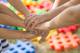  Picture of hands joined together with puzzle pieces in the background